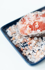 Fresh raw red salmon steak with large coarse pink salt prepared for baking on the grill lies on a blue plate. Healthy seafood food. Top view, place for an inscription.