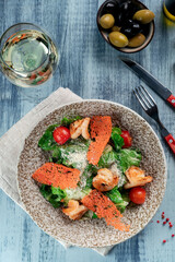 Caesar seafood salad with grilled shrimp, lettuce leaves, Croutons, Cherry tomatoes and Parmesan cheese served in a plate, top view