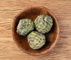 Fototapeta premium Sugar apples or custard apples in a bowl over wooden table
