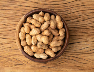 Shelled peanuts on a bowl over wooden table