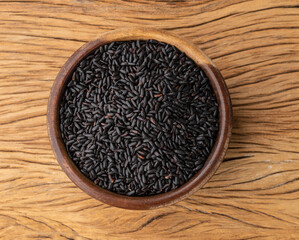 Raw black rice in a bowl over wooden table