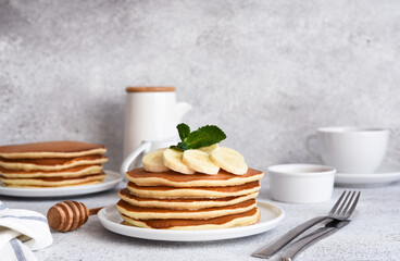 Stack of honey and banana pancakes on the kitchen table for breakfast.
