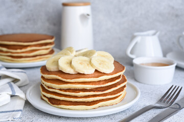 Stack of honey and banana pancakes on the kitchen table for breakfast.