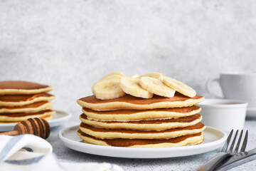 Stack of honey and banana pancakes on the kitchen table for breakfast.