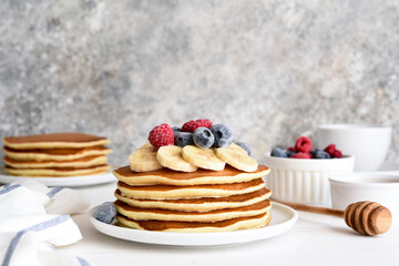 Stack of pancakes with berries and syrup on a kitchen table for breakfast. Good morning