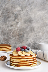 Stack of pancakes with berries and syrup on a kitchen table for breakfast. Good morning