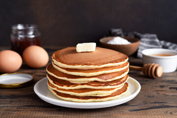 Blini or pancakes stack on wooden table with butter.  Maslenitsa holiday concept. Rustic style breakfast