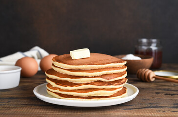 Blini or pancakes stack on wooden table with butter.  Maslenitsa holiday concept. Rustic style breakfast