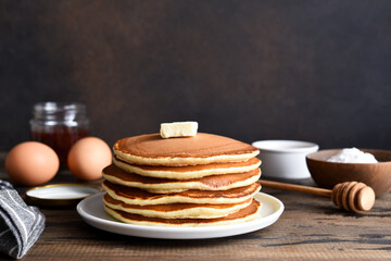 Blini or pancakes stack on wooden table with butter.  Maslenitsa holiday concept. Rustic style breakfast