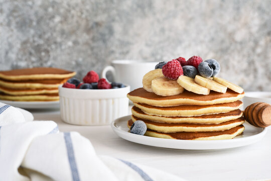 Stack of pancakes with berries and syrup on a kitchen table for breakfast. Good morning