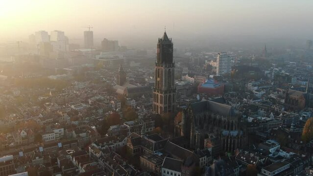 Cinematic aerial video of Utrecht historic city center with Dom church and foggy golden light 
