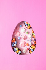 Chocolate easter eggs and decor flat lay for kids easter hunt egg concept on pink background. Sweets in the shape of an egg