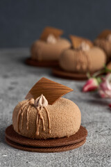 Mini mousse pastry dessert covered with chocolate velor on gray background.