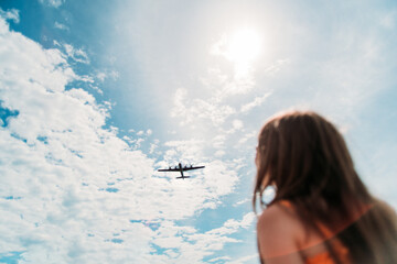 A girl watches a plane fly overhead - obrazy, fototapety, plakaty