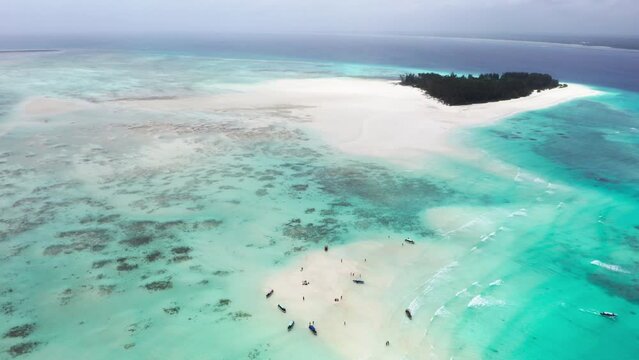 4K flying drone footage above white sandbanks coast with beautiful transparent rippled waves washing coral reefs atoll near Mnemba Island, Tanzania. Traveling in innocent Nature concept.