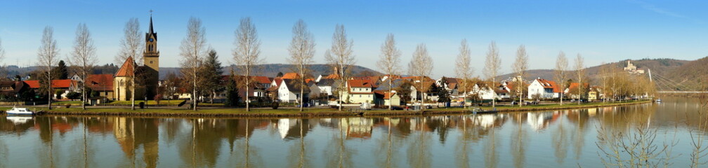 herrliches Panorama des Neckars bei Haßmersheim mit Spiegelung der Häuser und Bäume im Wasser - obrazy, fototapety, plakaty