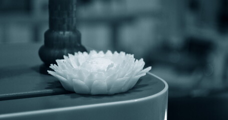 Abstract isolated object flower of yellow color printed on 3d printer blurred background. Fused deposition modeling, FDM. Progressive modern additive technology. Concept of 4.0 industrial revolution