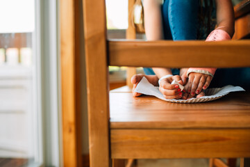 A girl paints her toenails on a chair