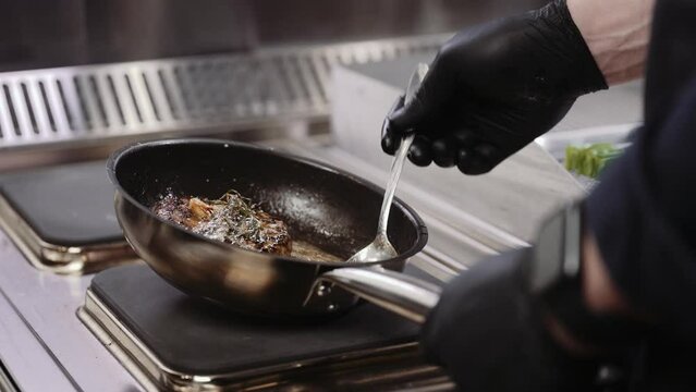 Professional chef cooks meat in a frying pan in a restaurant