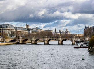 Fototapeta premium Seine embankment in Paris. View of the island of Cite and the bridge of Neuf. Beautiful breathtaking cityscape of the majestic famous ancient French city.