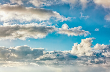 Daytime blue sky Background with white cumulus and tiny clouds. Soft focus.