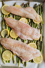 Raw pacific rockfish on a bed of asparagus and lemon wheels, sheet pan dinner. Making Trout Amandine. 