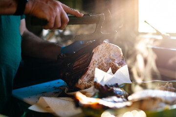A man carves a smoked turkey with a cooking axe.