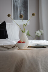 bed with pillows vase and strawberries in the bedroom. 