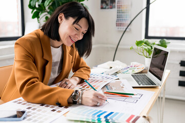 Architecture and interior design concept. Young businesswoman architect choosing materials and details for creating interior design project in studio. Freelancer woman working in a modern office
