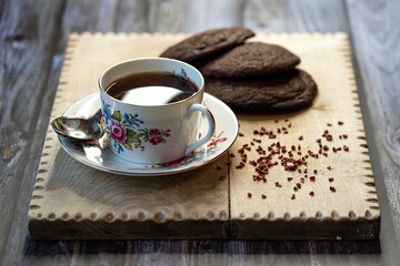 A cup of black tea with homemade chocolate cookies on a wooden plate