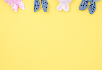pink and blue fabric bunny ears on a yellow background. Easter concept.