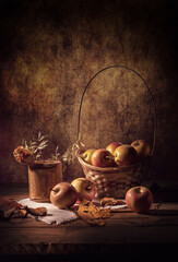 Still life apples in a basket, on a wooden table with a white salfette, and a rose in a birch bark vase, on a colorful background
