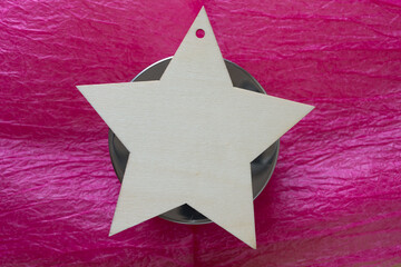 wooden star on a metal object on pink tissue paper