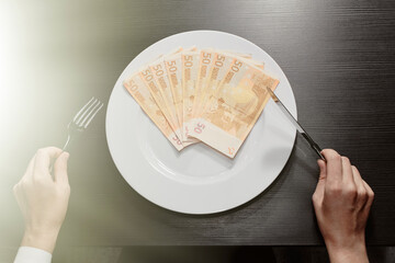 Money on a plate with a fork and knife. Euro banknotes. Wealth and the greed of cash. Business.