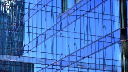 Fragments of building in business district of modern city. High-rise office building in downtown. Modern architecture of typical concrete, glass and steel.