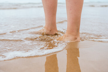 close-up of female feet walking on the sand on the shore of the beach