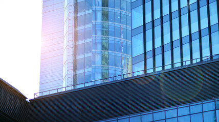 Fototapeta na wymiar Fragments of building in business district of modern city. High-rise office building in downtown. Modern architecture of typical concrete, glass and steel.