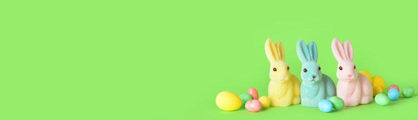 Cute Easter bunnies and eggs on green background with space for text