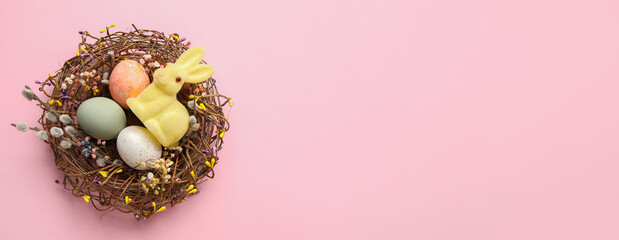 Nest with painted Easter eggs and bunny on pink background with space for text