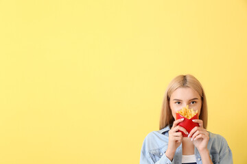Young woman with french fries on yellow background