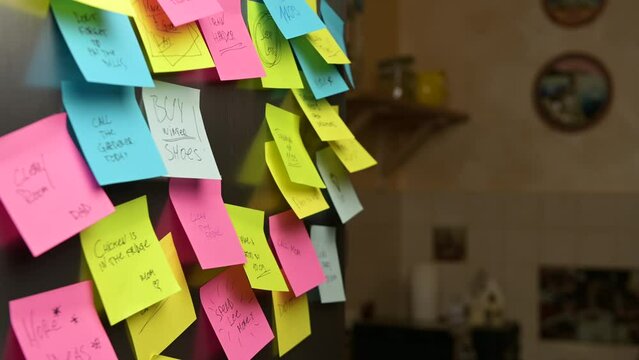 A young woman walks up to the refrigerator door, finds the note she needs, and tears off this sticker.