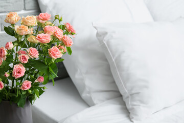 Vase with bouquet of beautiful fresh roses in bedroom, closeup