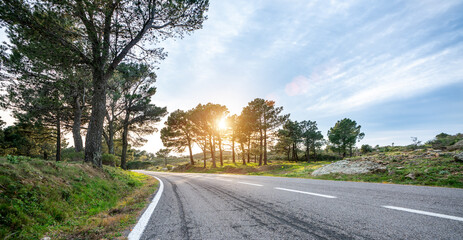 Empty long mountain road to the horizon on a sunny summer day at bright sunset