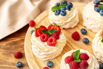 Board of tasty Pavlova cakes with fresh berries on wooden background, closeup