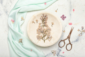 Composition with dried pressed lilac flowers and scissors on white background