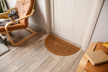 Stylish mat near light wooden door in hall