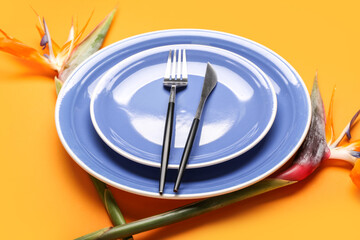 Simple table setting with bird of paradise flowers on orange background