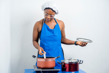 image of uniformed african woman in front of cooking wares, stiring- food concept 
