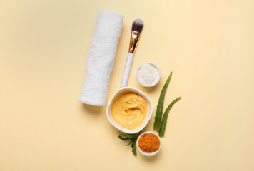 Bowls with turmeric mask, powder, makeup brush and aloe on beige background