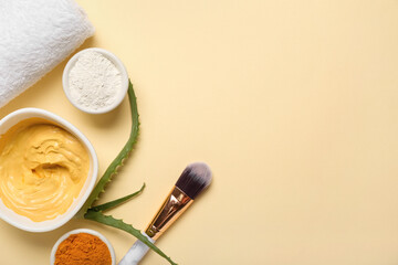 Bowls with turmeric mask, powder, makeup brush and aloe on beige background